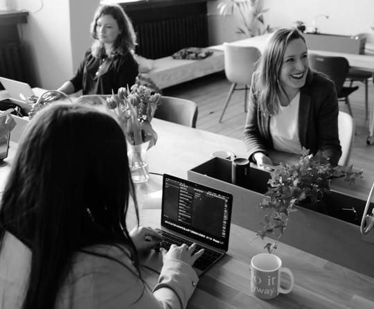 woman smiling with a woman on a computer